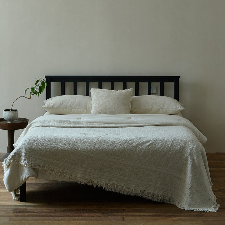 Massive wooden bed with upright slatted headboard and natural linen bedding