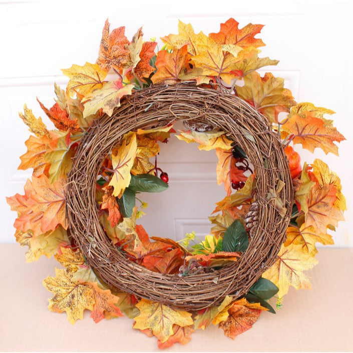 Autumn door wreath with artificial maple leaves, cones, and decorative pumpkins