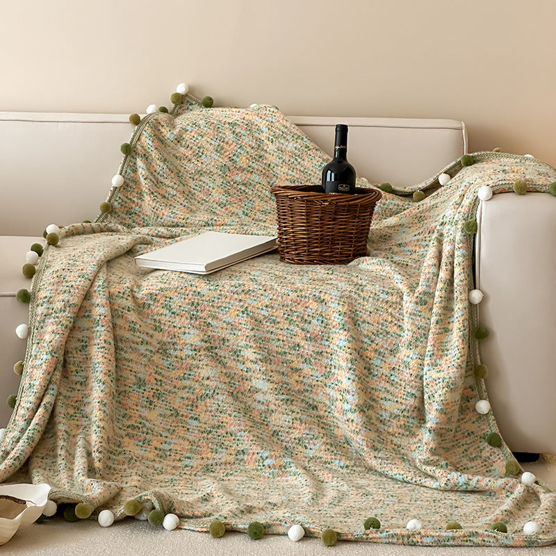 Cozy throw blanket with pom pom trim and mottled texture