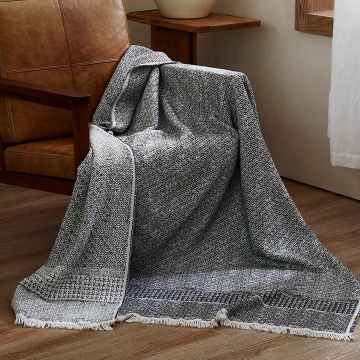 Large cozy living blanket made of cotton blend fabric with geometric jacquard pattern and fringed hem