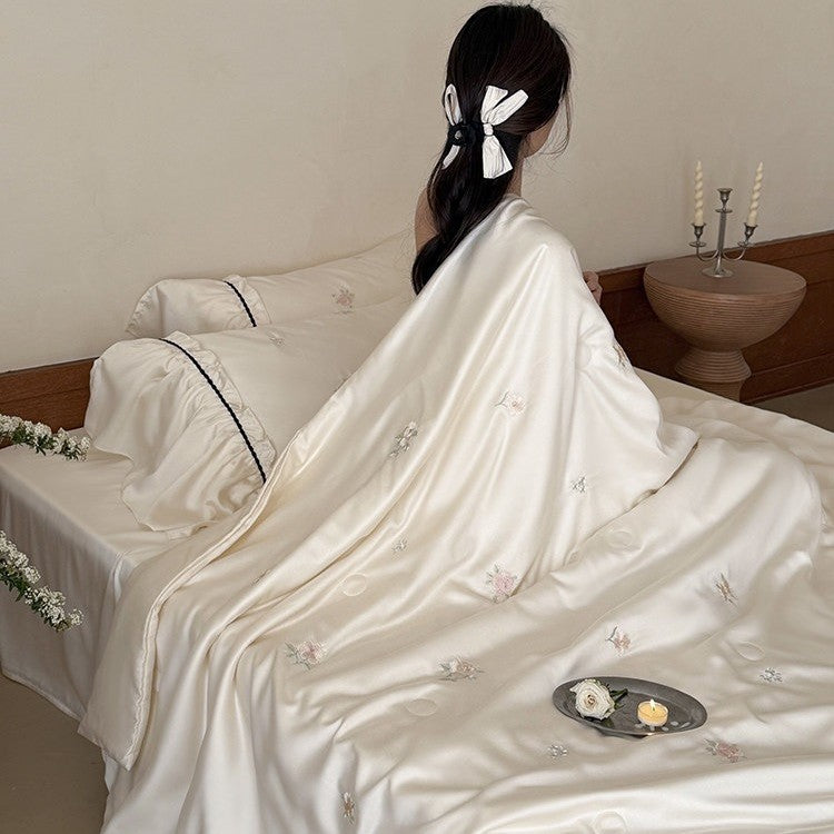 Exquisite satin bedding set with floral embroidery, gathered pillow shams, and contrasting piping
