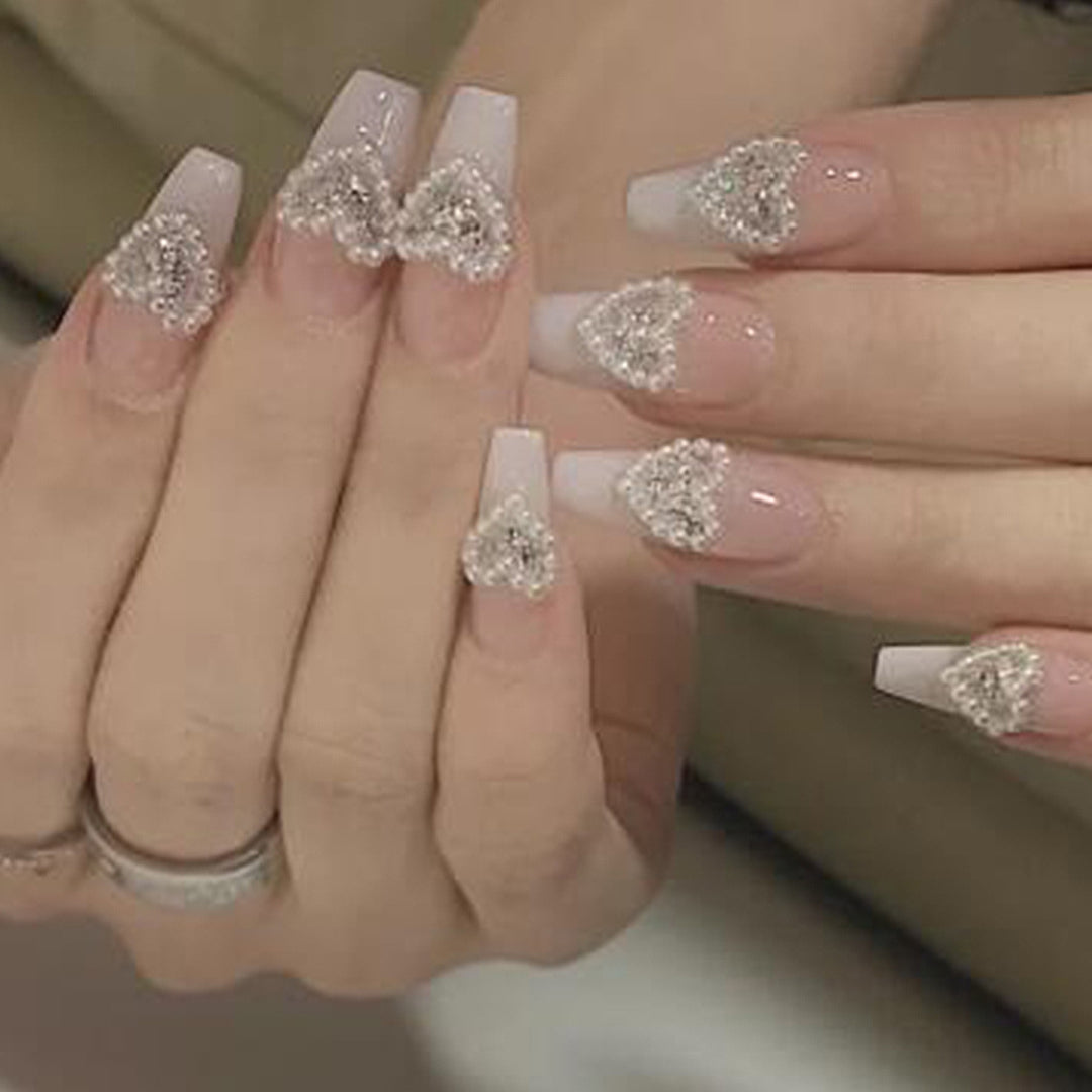 Artificial nail art with heart and rhinestone decorations Kalsten