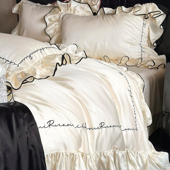 Luxurious cotton satin bedding set with ruffled flounces, contrasting piping & calligraphic embroidery