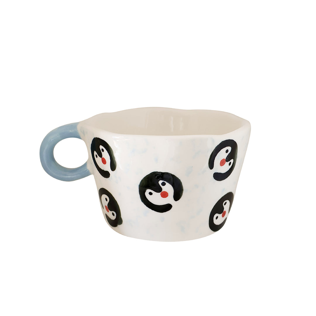 Ceramic coffee mug with hand-painted penguin designs and ergonomic handle