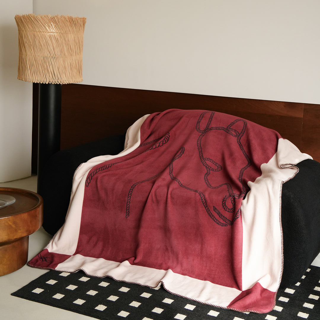 Throw blanket with embroidered cord motif and decorative stitching