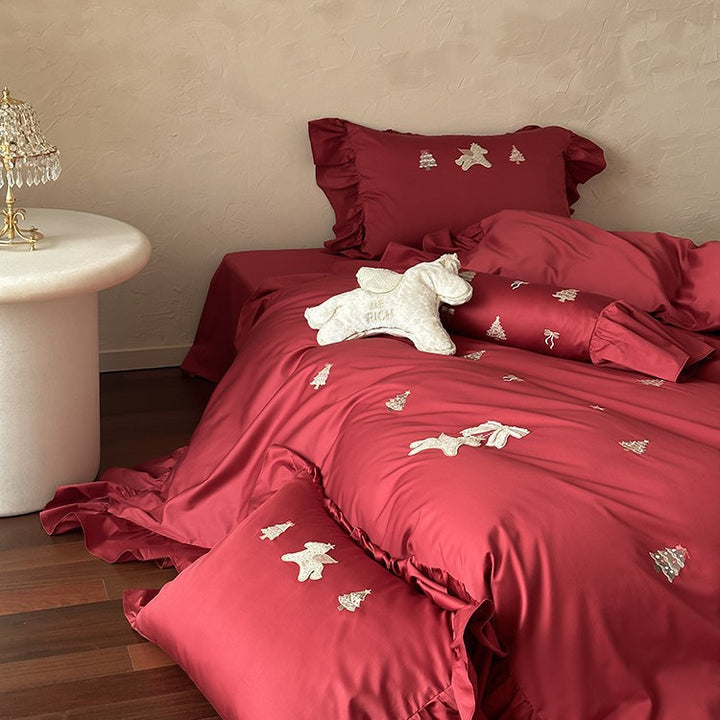 Festive satin bedding set with embroidered pine and mythical creature appliqués and ruffled cushion