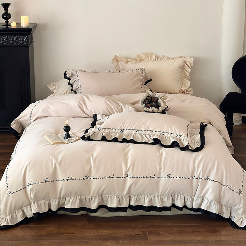 Luxurious cotton satin bedding set with ruffle, contrasting piped trim, and calligraphic embroidery