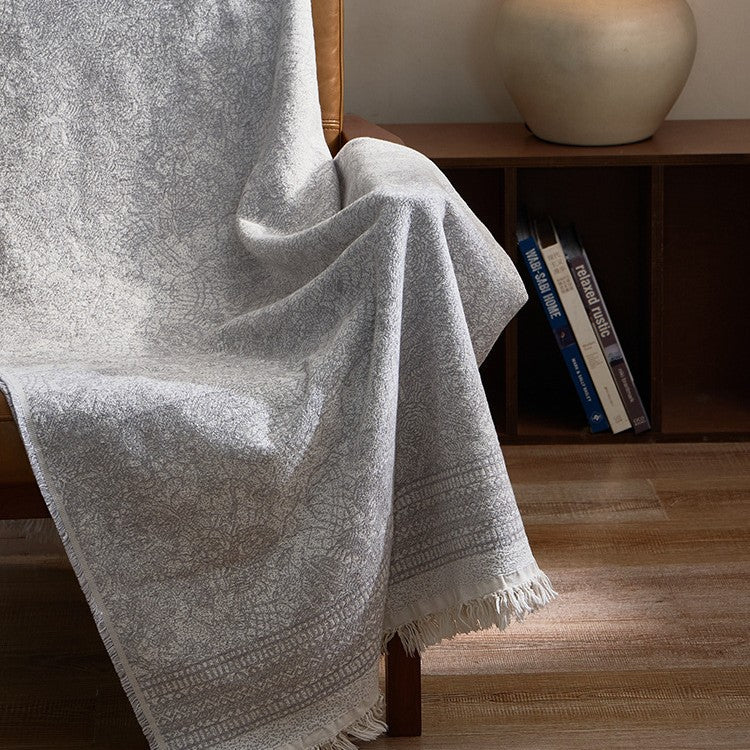 Large cozy living blanket made of cotton blend fabric with geometric jacquard pattern and fringed hem