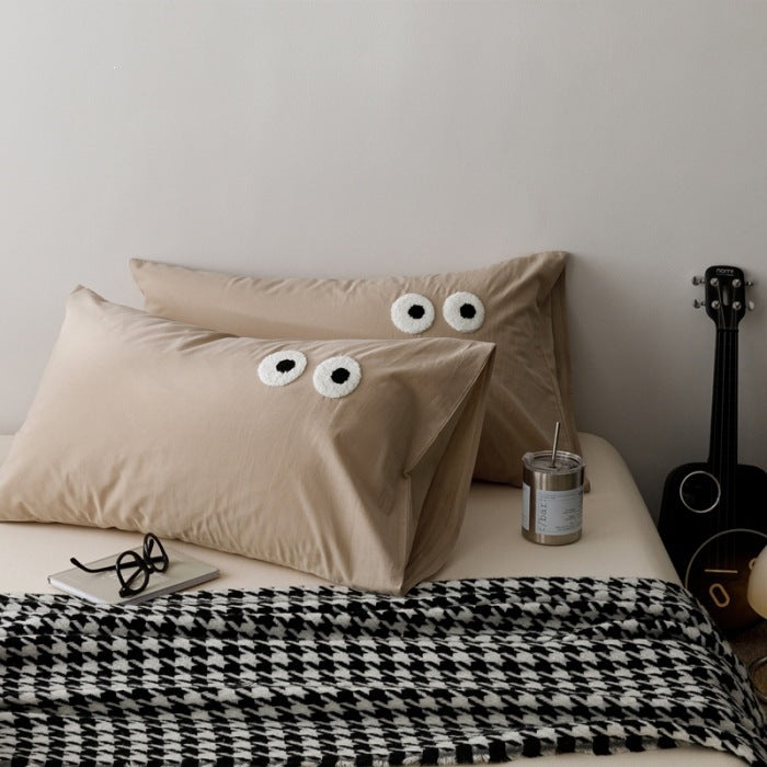 Playful cushion cover set with embroidered eye appliqués made of soft cotton fabric