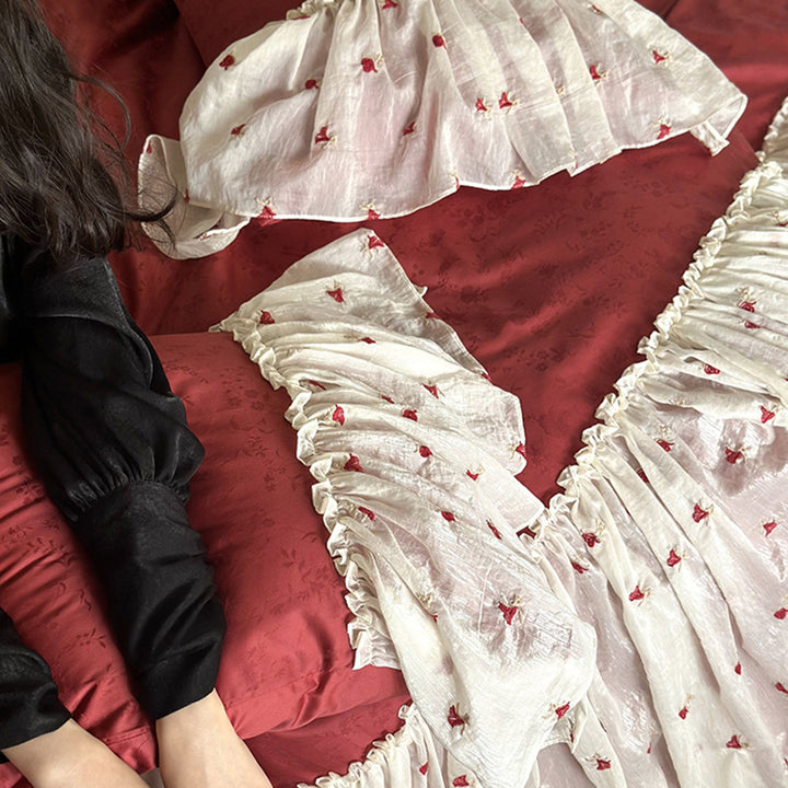 Ruffled bedskirt and pillowcases made of embroidered cotton-linen blend