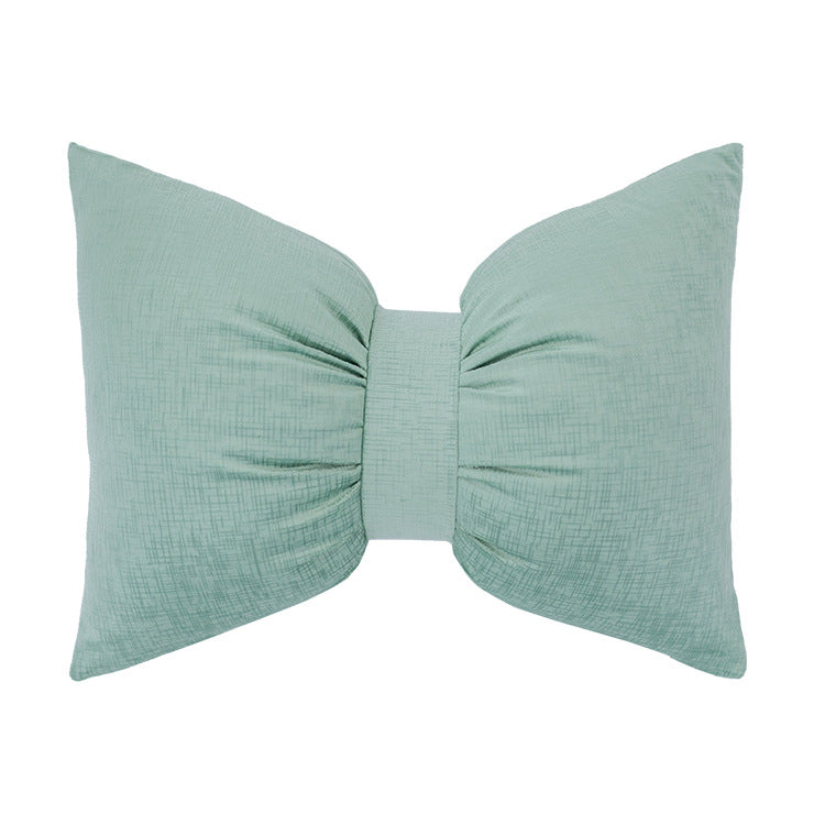 Bow-shaped decorative cushion with central band detail and structured fabric look