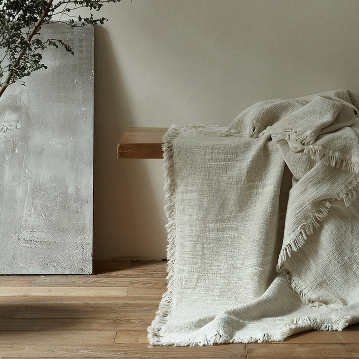 Massive wooden bed with upright slatted headboard and natural linen bedding