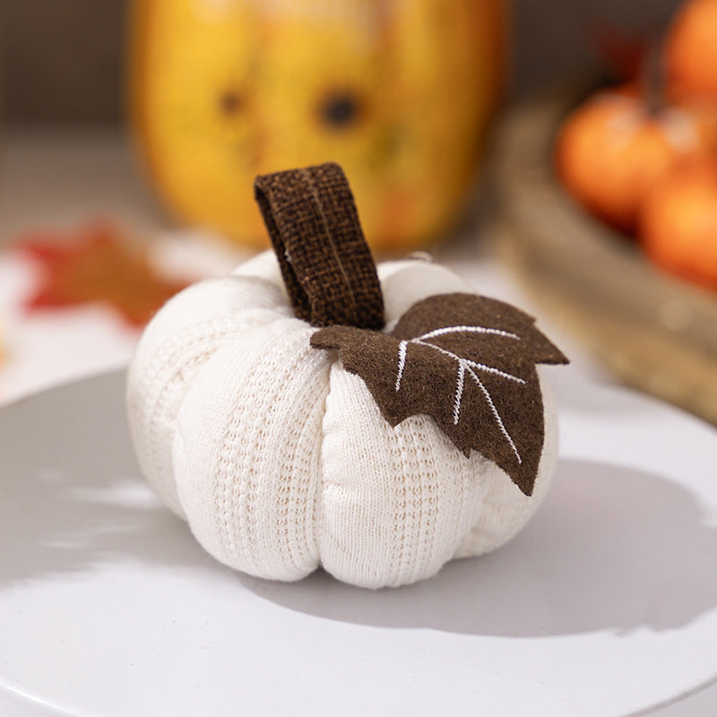Knitted fabric pumpkin as autumn table decoration with felt leaf