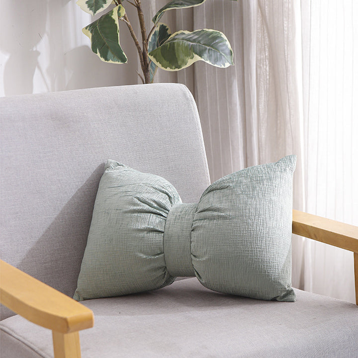Bow-shaped decorative cushion with central band detail and structured fabric look