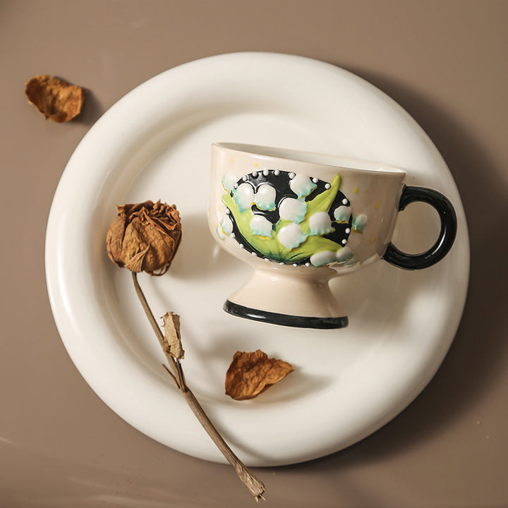Ceramic foot cup with hand-painted lily of the valley relief and round handle