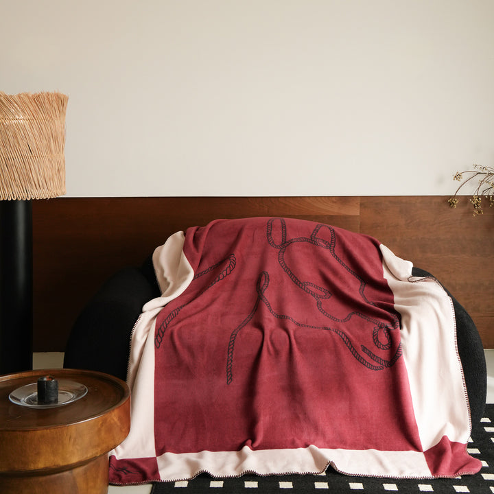 Throw blanket with embroidered cord motif and decorative stitching