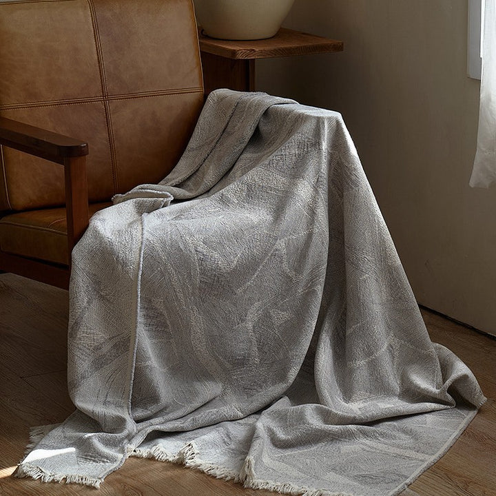 Large cozy living blanket made of cotton blend fabric with geometric jacquard pattern and fringed hem