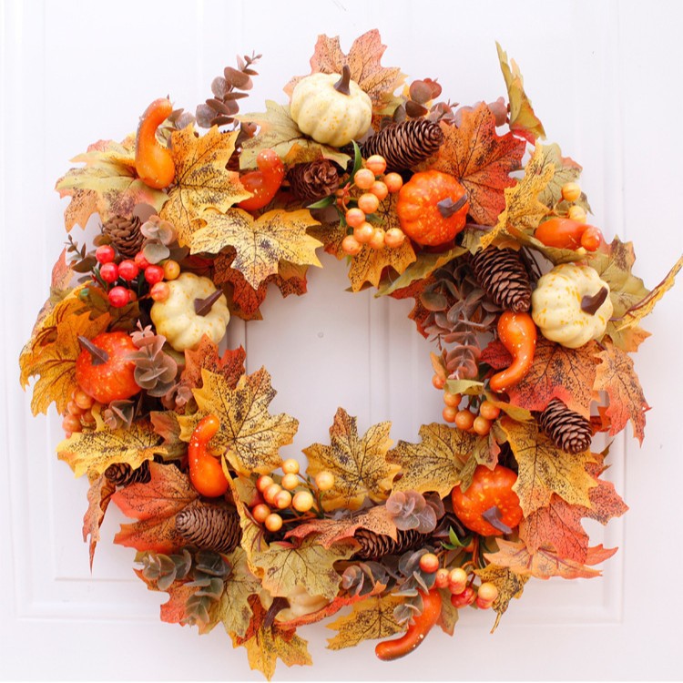 Autumn door wreath with artificial maple leaves, cones, and decorative pumpkins
