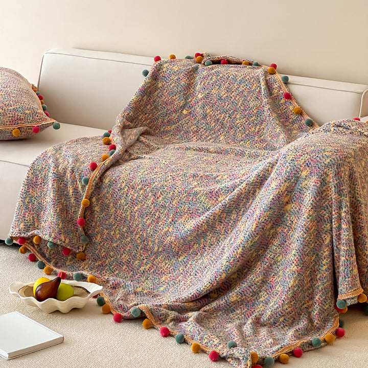 Cozy throw blanket with pom pom trim and mottled texture