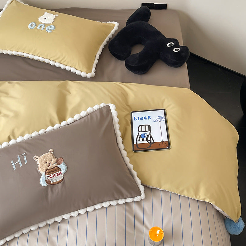 Children's bed set with teddy bear embroidery, pom-pom edging, and reversible blanket