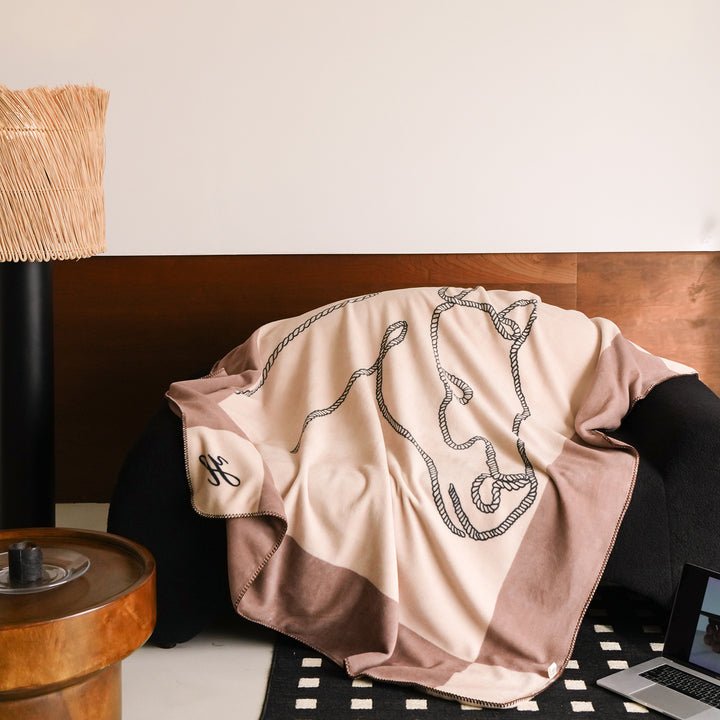 Throw blanket with embroidered cord motif and decorative stitching