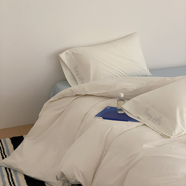 Cotton satin bed linen set with contrasting piping and subtle brand embroidery