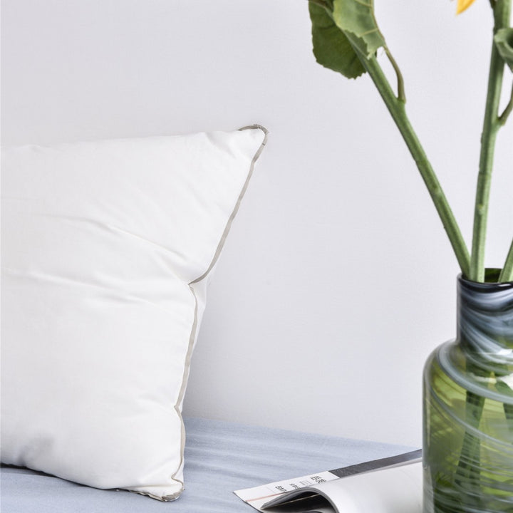 Comfort pillow with shape-stable hollow fiber filling and contrasting piping