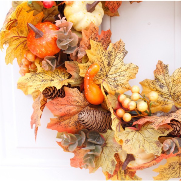 Autumn door wreath with artificial maple leaves, cones, and decorative pumpkins