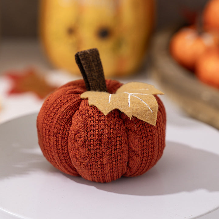 Knitted fabric pumpkin as autumn table decoration with felt leaf