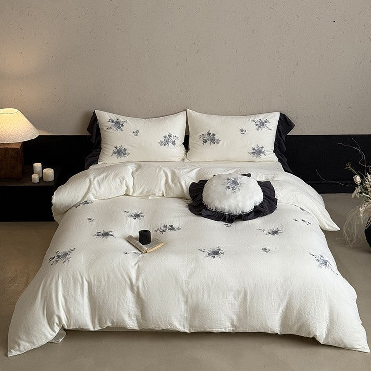 Cotton muslin bedding set with embroidered rose emblems and fine ruffle