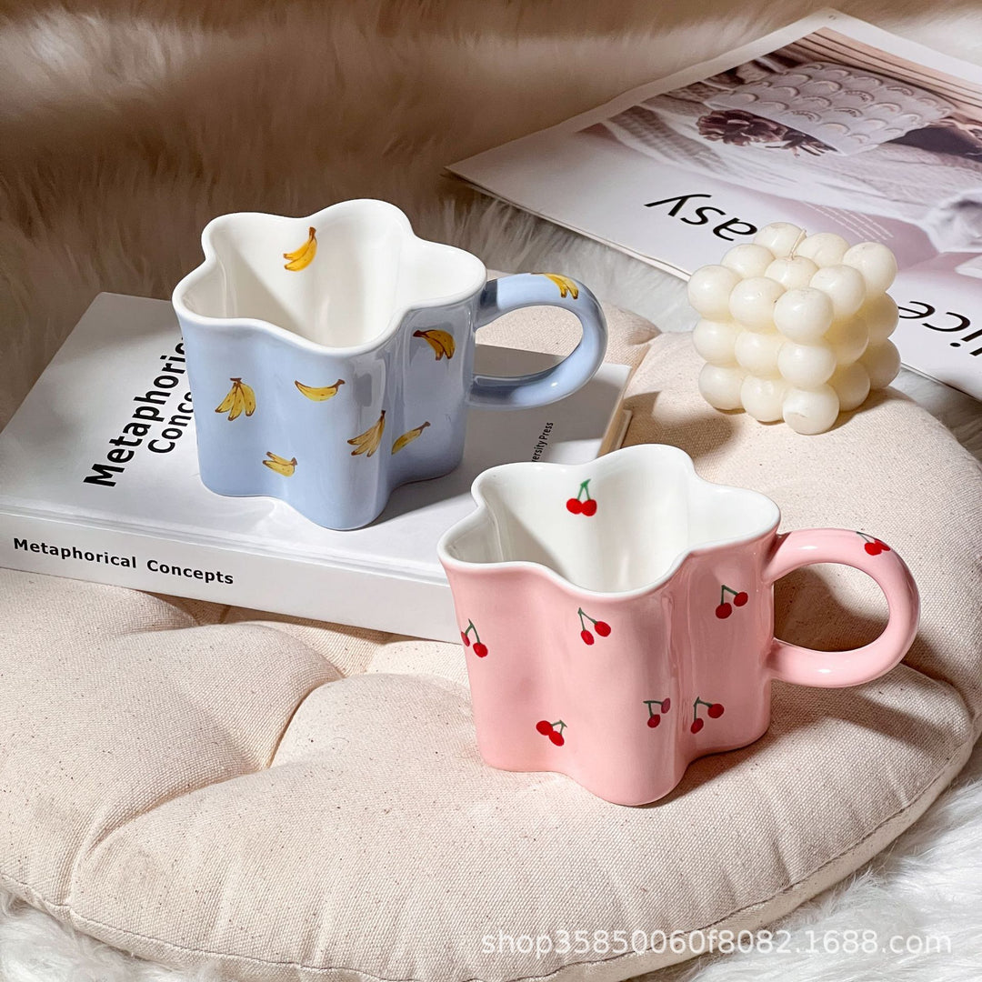 Ceramic coffee mug with flower-shaped wavy rim, illustrative banana decor and ergonomic handle