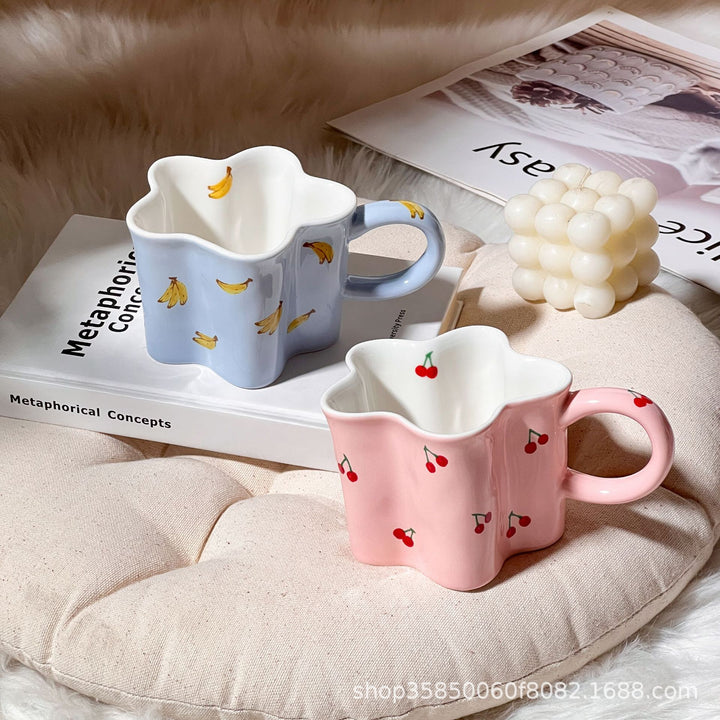 Ceramic coffee mug with flower-shaped wavy rim, illustrative banana decor and ergonomic handle