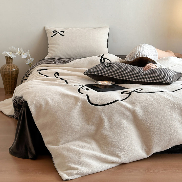 Reversible microfiber bedding set with plush surface, pom-pom corners, and paw embroidery