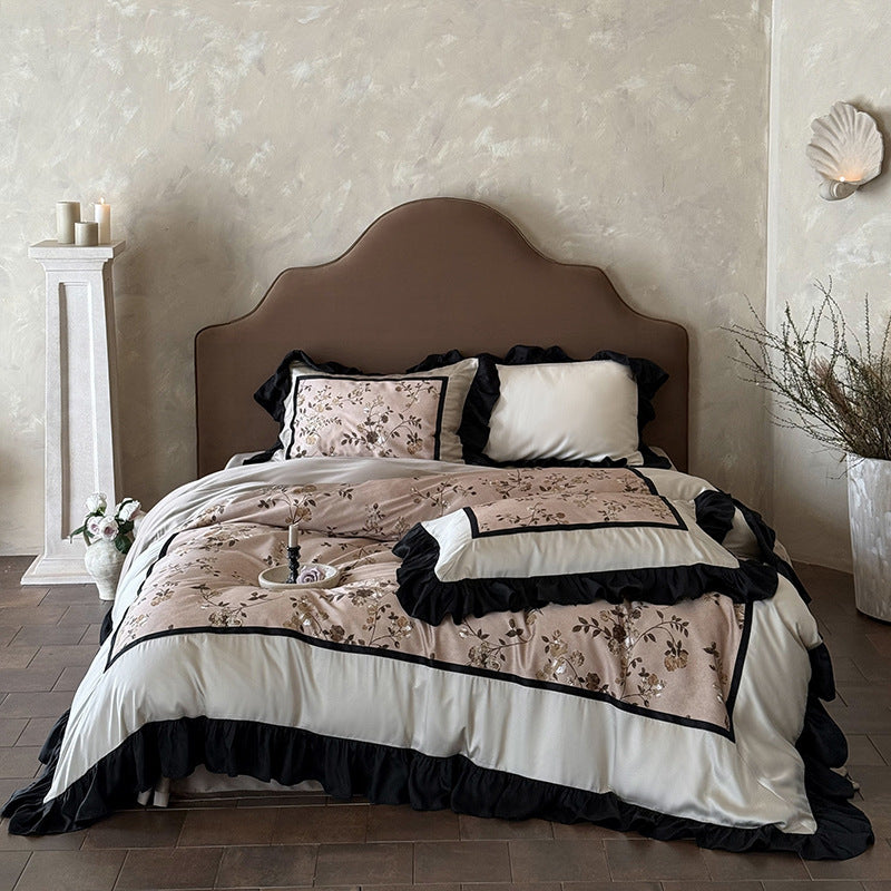 Satin bedding set with embroidered flower appliqués, layered flounce and decorative cushion