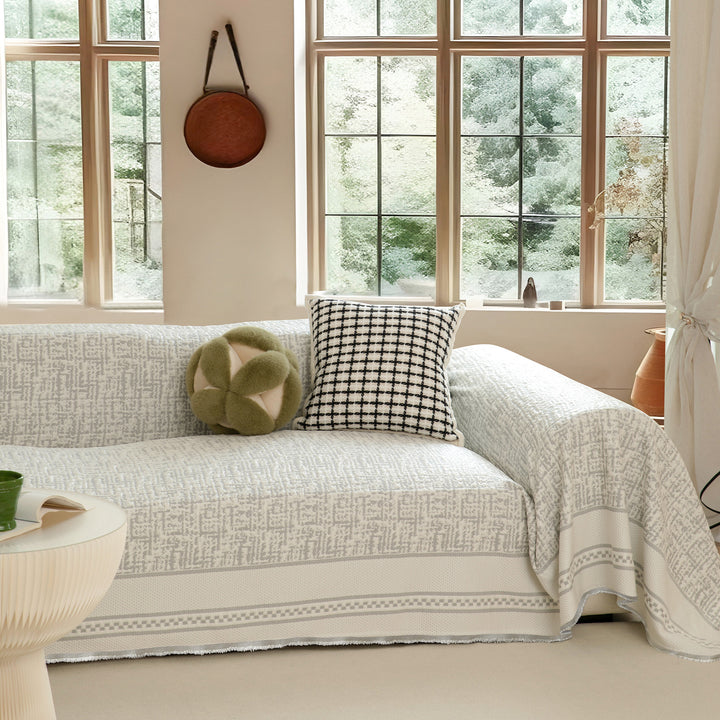 Geometric sofa cover made of cotton blend fabric with decorative fringe edge