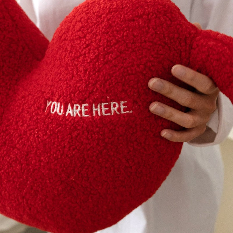 Cuddle pillow in heart shape with extra long arms made of sherpa fleece and embroidery detail