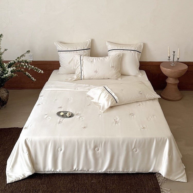 Exquisite satin bedding set with floral embroidery, gathered pillow shams, and contrasting piping