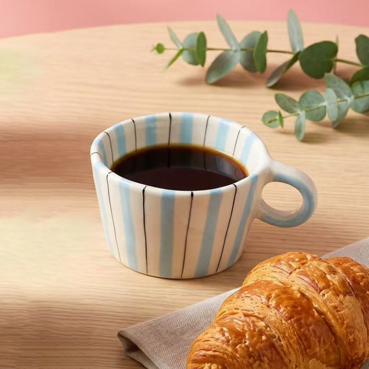 Ceramic coffee mug with ergonomic round handle and fine striped texture