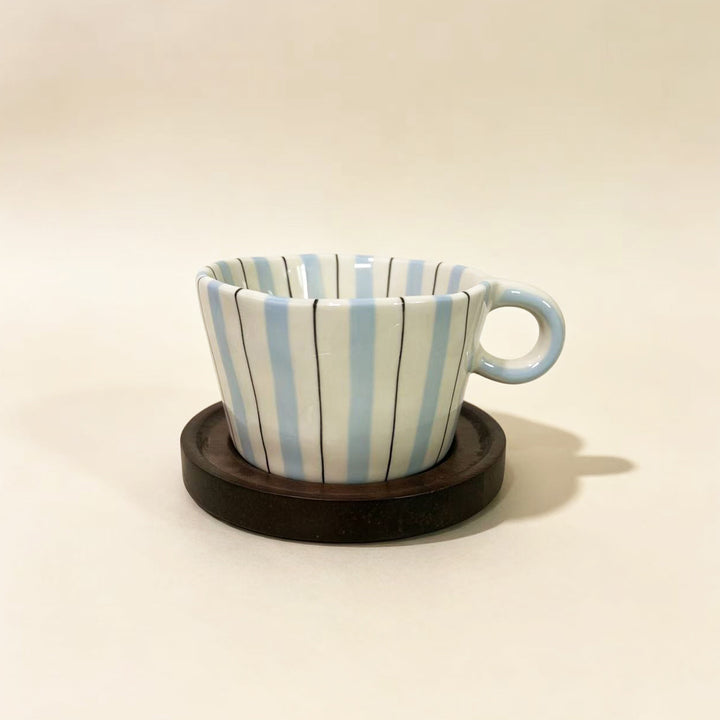 Ceramic espresso cup with round wooden coaster and handcrafted stripe pattern