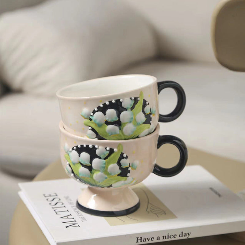 Ceramic foot cup with hand-painted lily of the valley relief and round handle