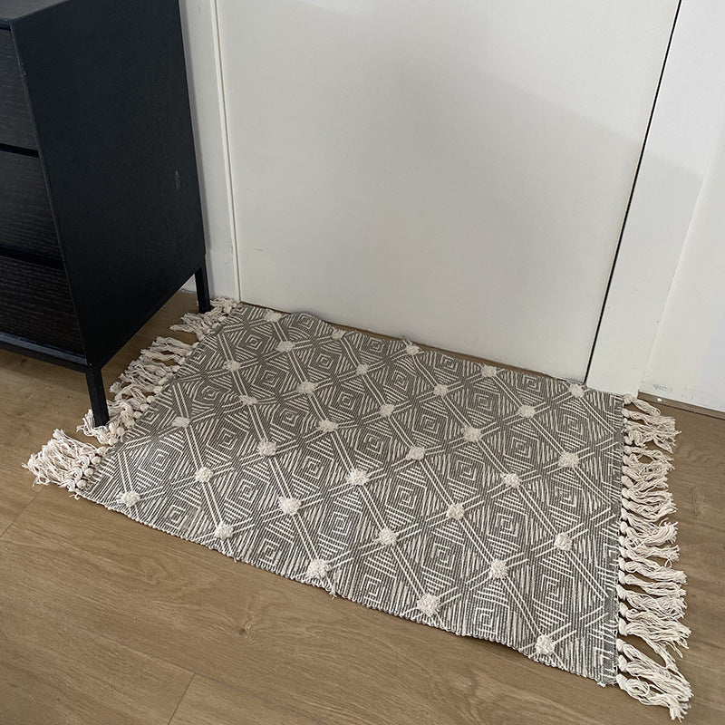 Hand-tufted bathroom mat with fringes, decorative dot-and-dash pattern and non-slip backing Kalsten