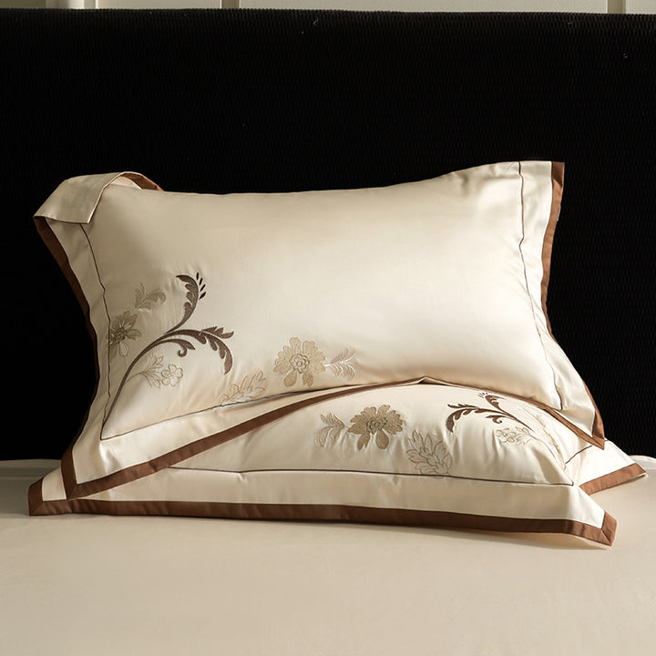 Luxurious embroidered satin bed linen set with floral corner motif and contrast piping