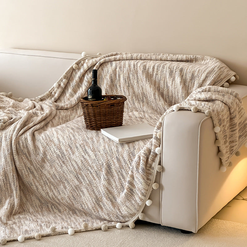 Cozy throw blanket with pom pom trim and mottled texture