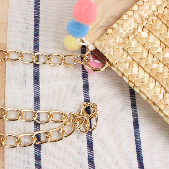Clutch made of handwoven natural material with decorative pompons Kalsten