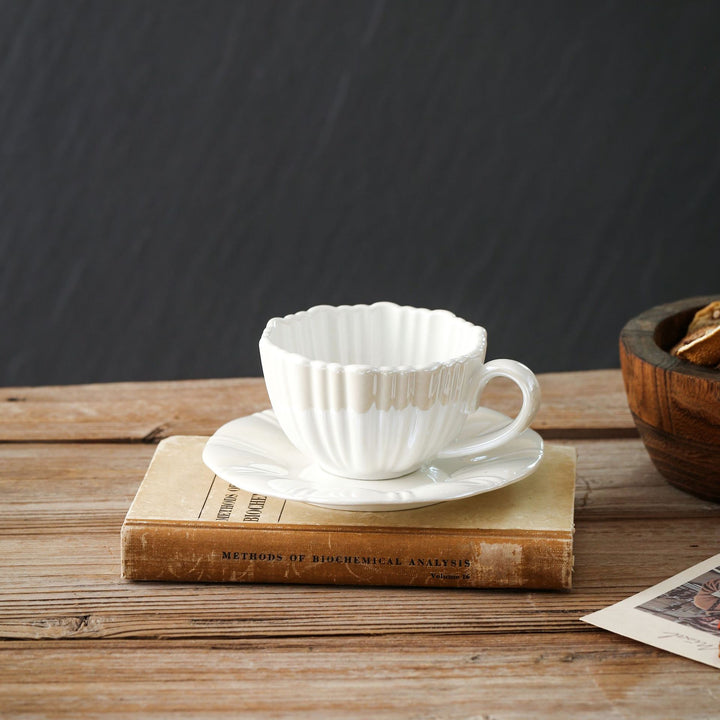 Fine porcelain tea cup with ribbed shell shape and matching saucer