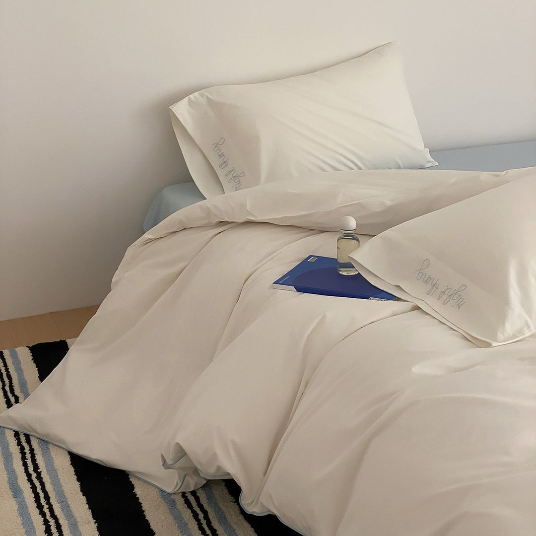 Cotton satin bed linen set with contrasting piping and subtle brand embroidery