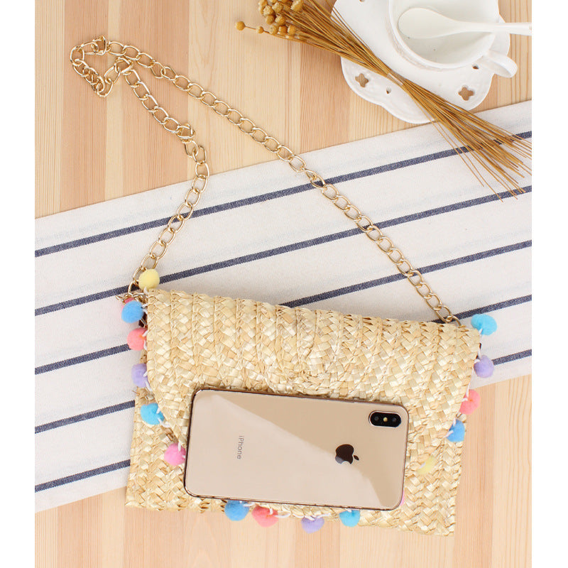 Clutch made of handwoven natural material with decorative pompons Kalsten