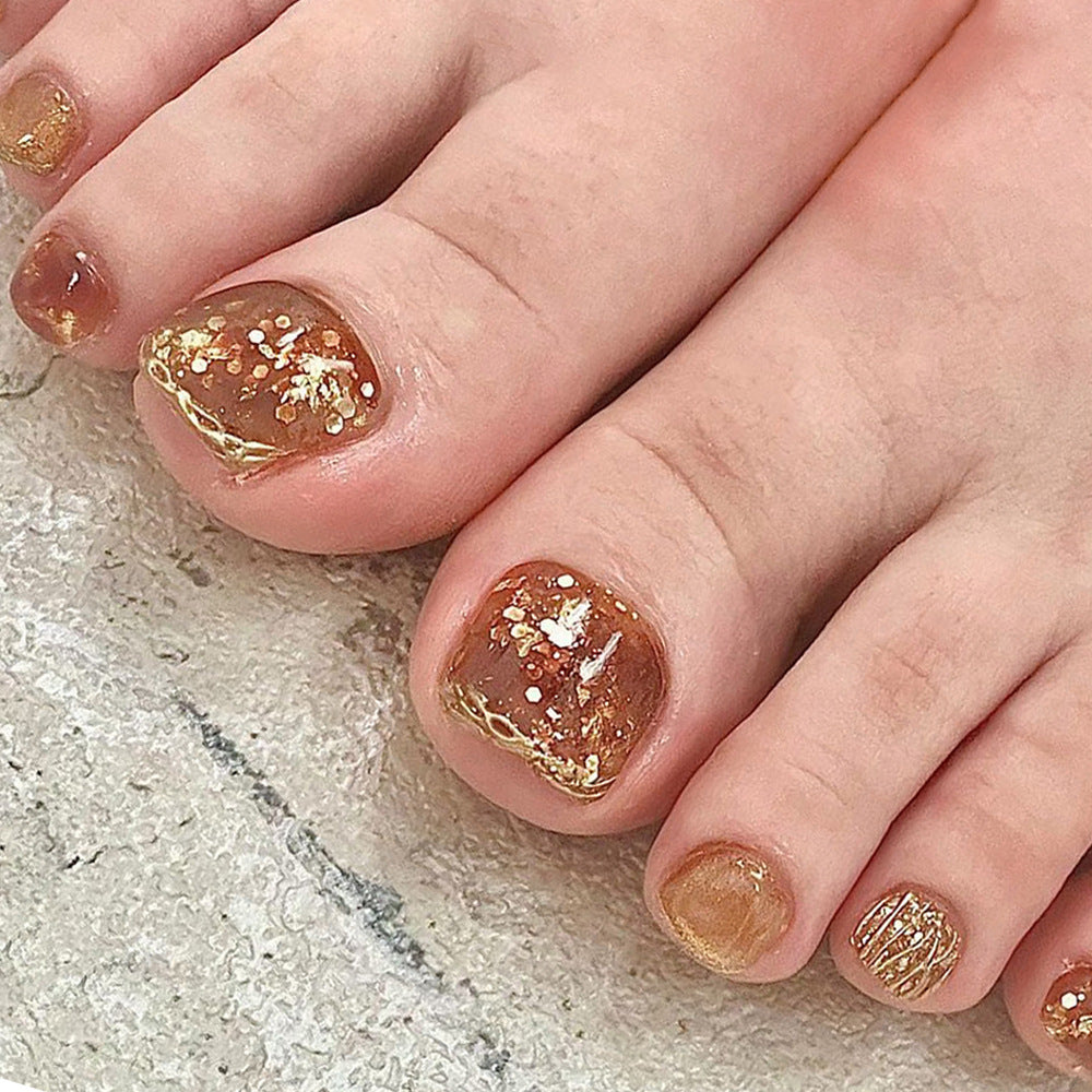 Artistic toenail design with glitter and golden accents Kalsten
