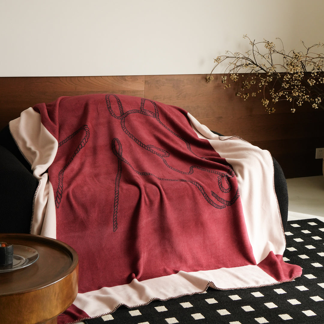 Throw blanket with embroidered cord motif and decorative stitching