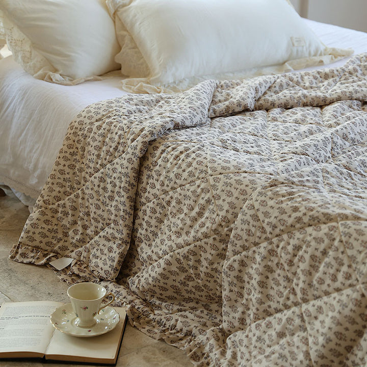 Lightly quilted throw blanket in vintage floral print with ruffled edge